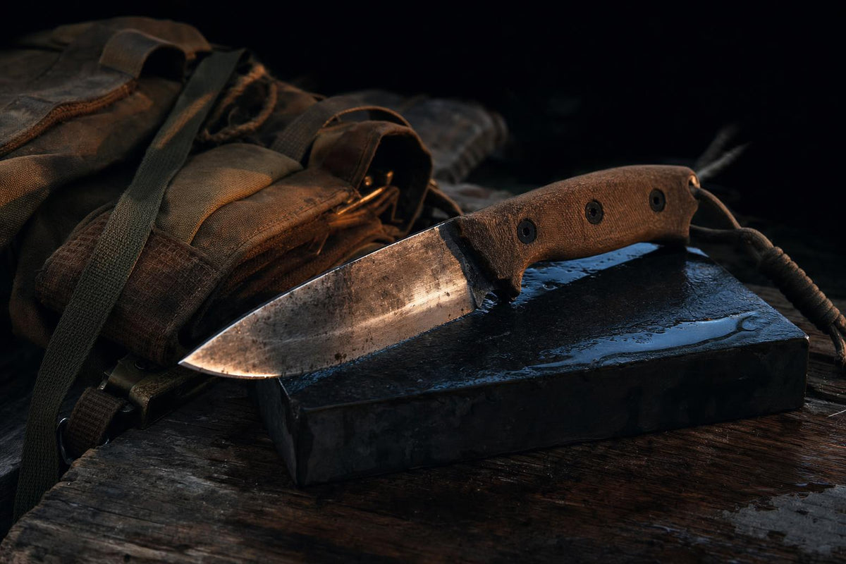 fixed blade survival knife on sharpening stone in dark field sharpening setup